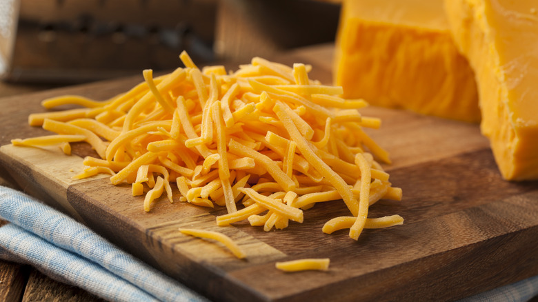 Shredded cheese on cutting board