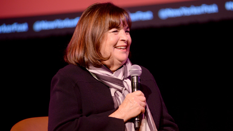 Ina Garten smiles while holding a microphone during an event