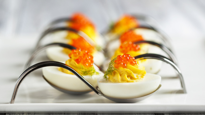 Deviled eggs with roe and dill on white platter