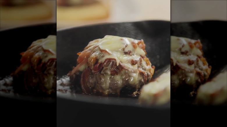 Burgers cooking in a pan.