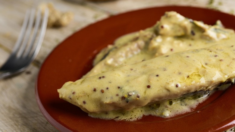 White spoon filled with dijon mustard with bowls of mustard around it