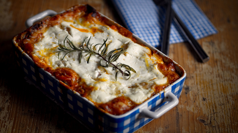 Lasagne garnished with rosemary in a casserole dish