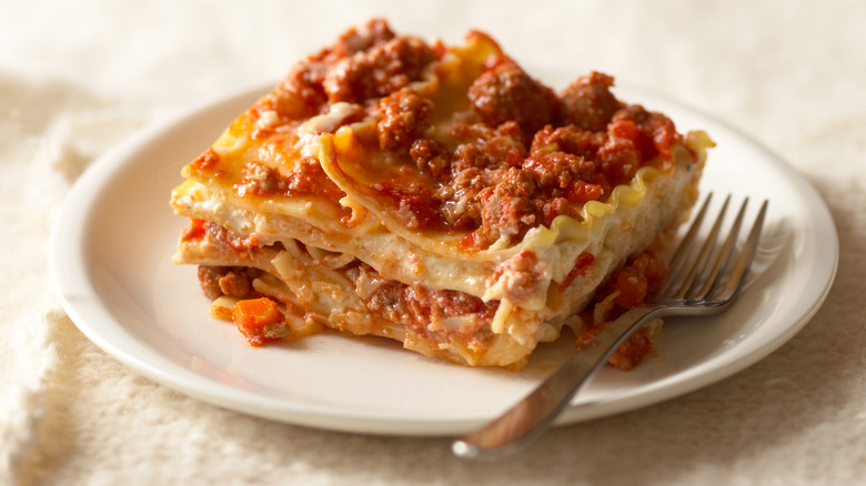 Piece of cooked lasagna on a plate with a fork