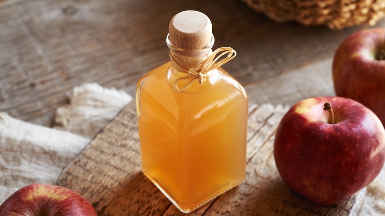 Apple cider vinegar in glass bottle with apples