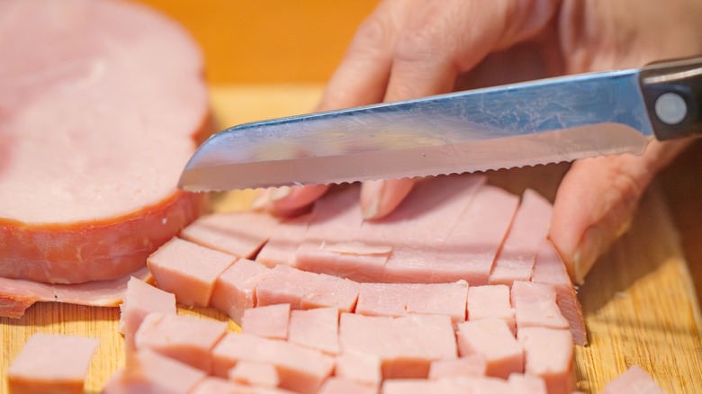 Person dicing ham on cutting board