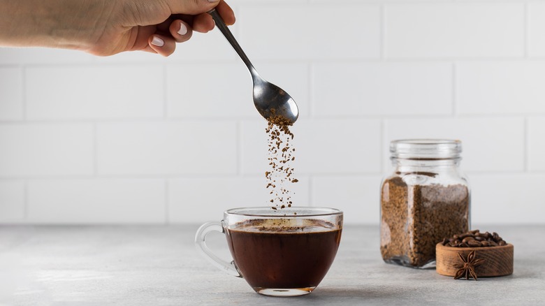 Hand pouring instant coffee into cup