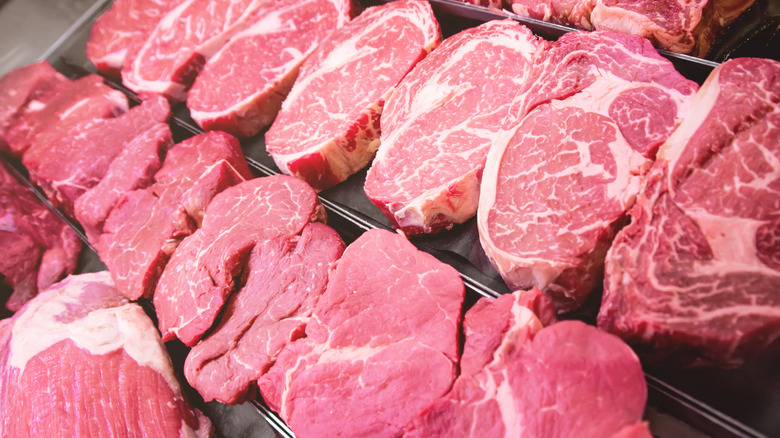 Raw steaks and other red meat lined up together on a rack