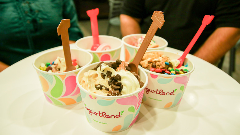 different frozen yogurt cups filled with mnm and chocolate toppings