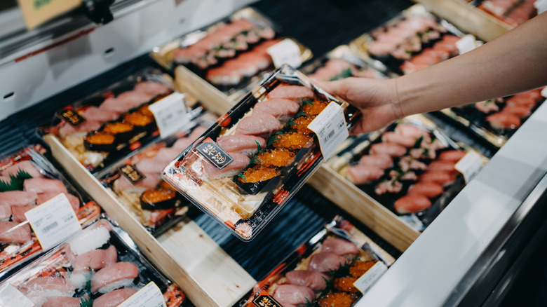 Person picking up grocery store sushi