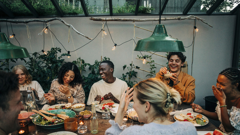 Wedding guests sitting together at a long outdoor table for a dinner party