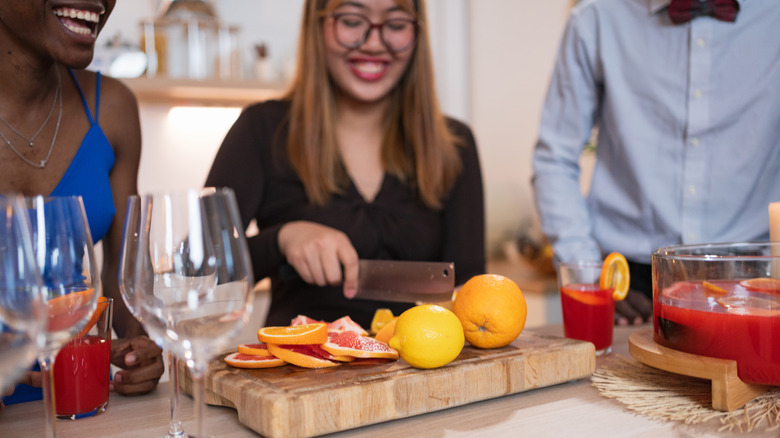 A group of friends laughing and making cocktails together at home