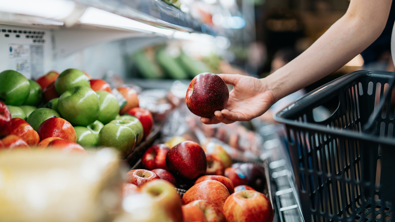 grocery shopper picking up apple