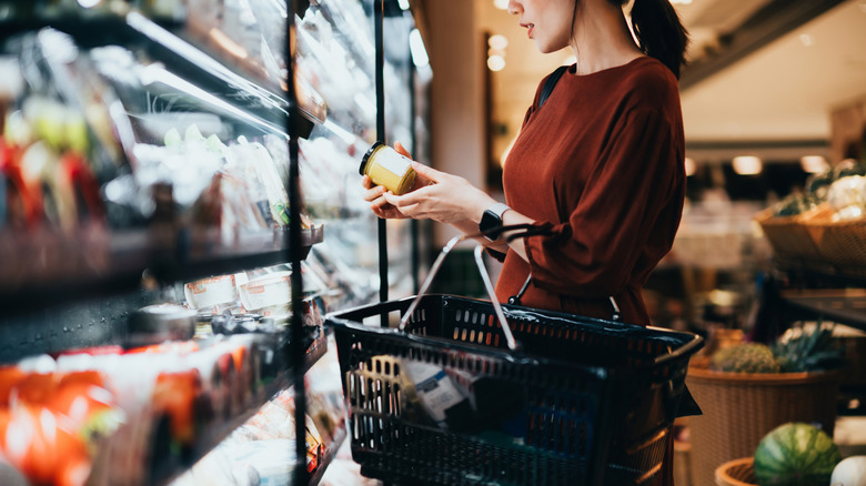 woman at grocery store holding small jar