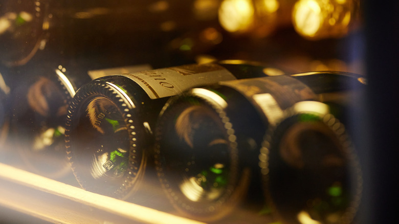 Wine bottles lying on their side inside a wine fridge.