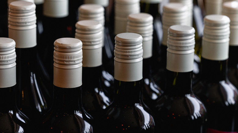 The top half of several bottles of wine with all-white caps.