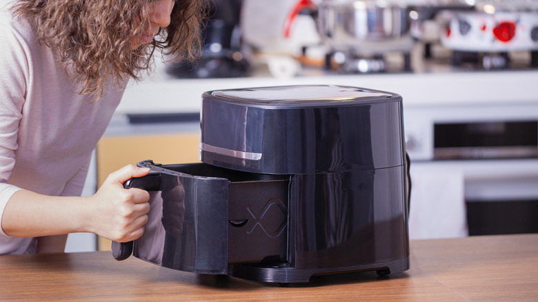 woman cooking something in an air fryer