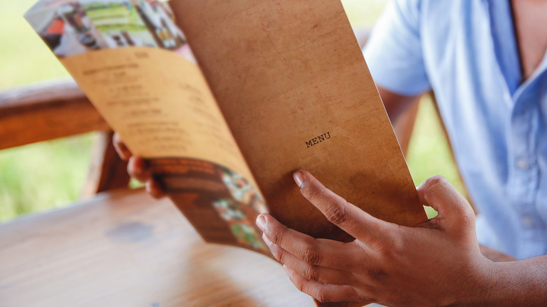 man holds open menu in hands