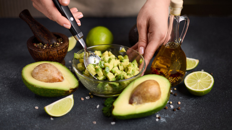 a woman stirs avocado chunks with a spoon