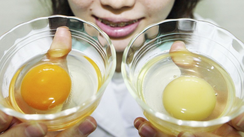 Person holding bowls of egg yolk