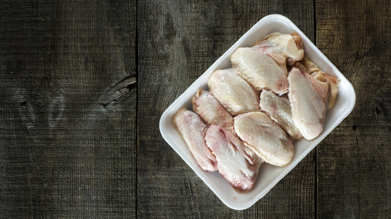 a package of raw chicken wings against a wooden background