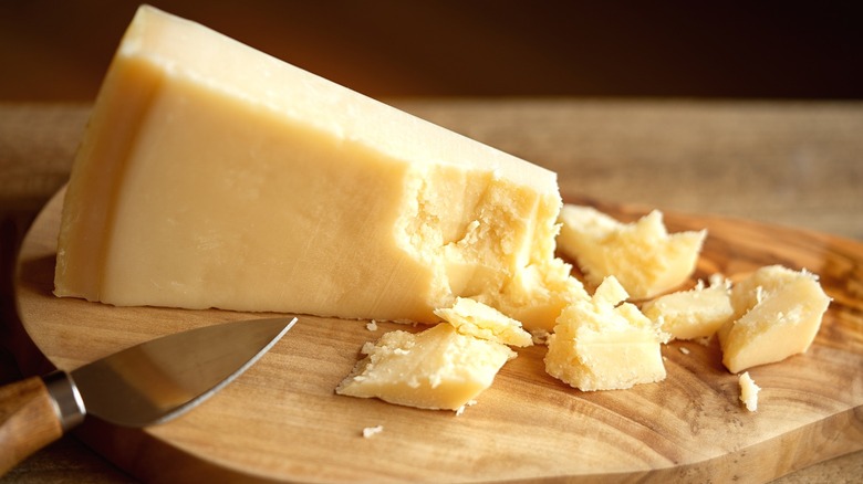 A wedge of Parmigiano Reggiano cheese on a wooden block