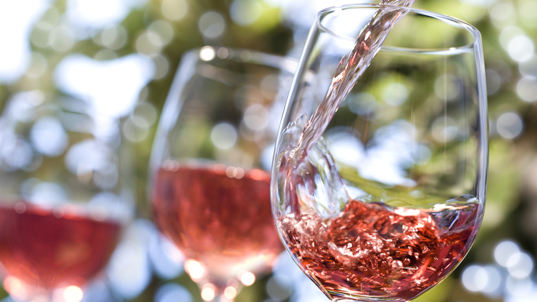 Three glasses of rosé wine being poured