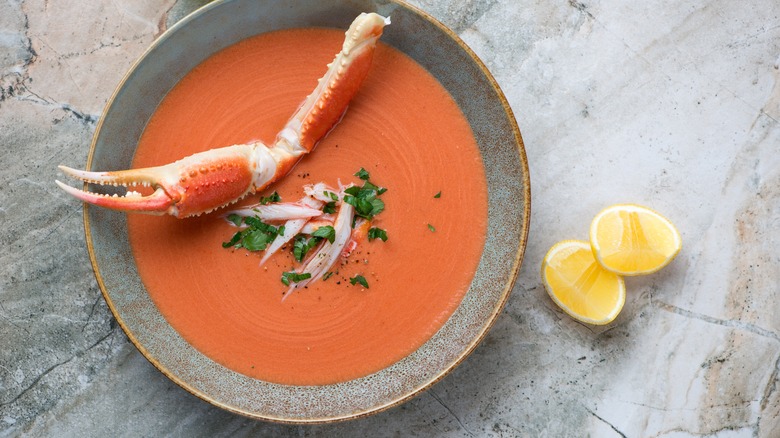 A bowl of crab bisque with a crab claw on top