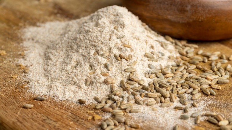 Spelt flour with whole grains on a wooden board