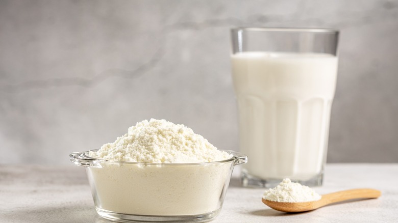 A bowl of powdered milk, next to a glass of non-powdered milk