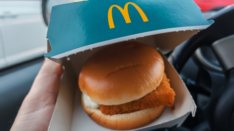 person in car holding boxed McDonalds Filet-O-Fish sandwich