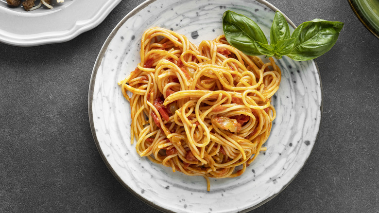 Spaghetti in tomato sauce, served on a white plate.