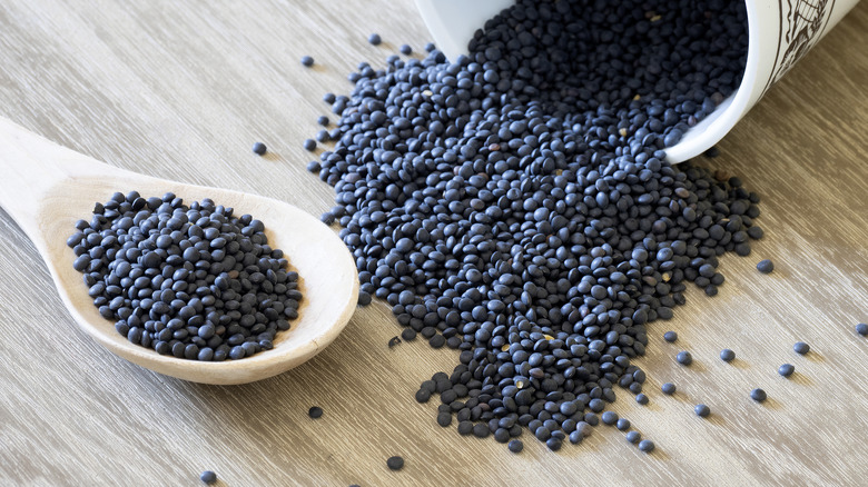 Black lentils that have spilled from a dish.