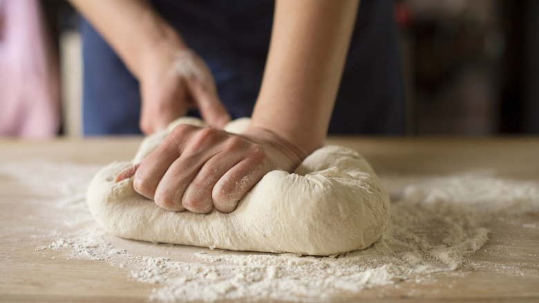 Someone kneading dough on a cutting board with flour