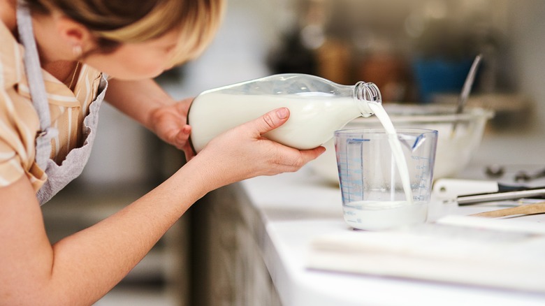 woman pouring milk into measuring cup