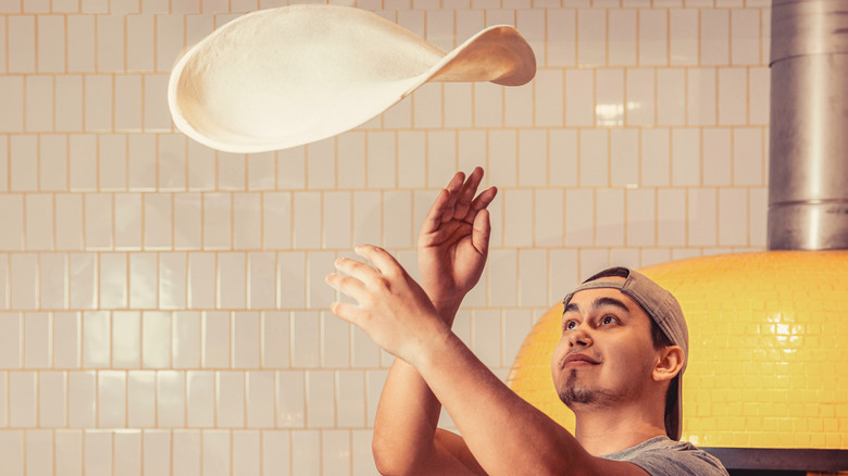 A chef tossing pizza dough in the air at a pizzeria