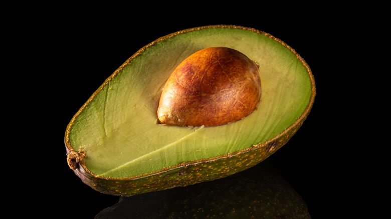 Half an avocado with a pit on a black background