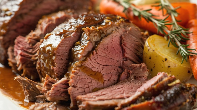 A pot roast served with carrots and potatoes.