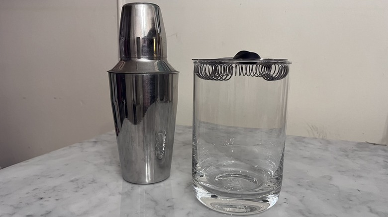 A cocktail shaker and a mixing glass with strainer