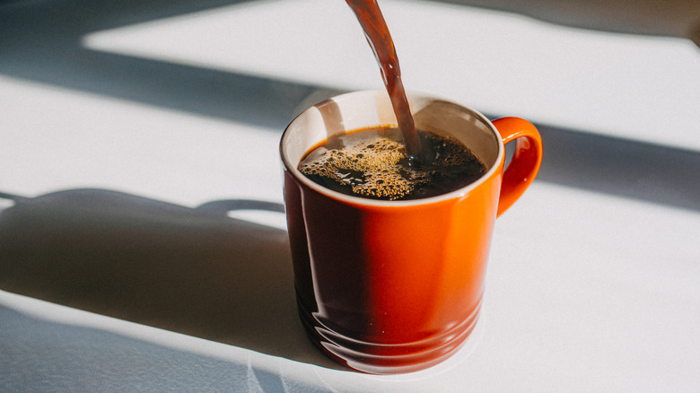 Coffee being poured into orange mug