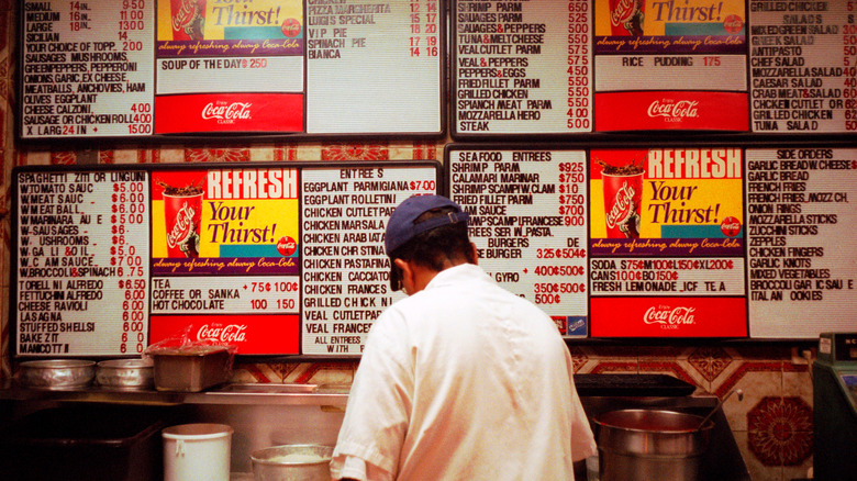 Pizza chef before menu wall at Italian restaurant in New York