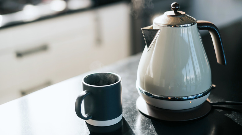 A white, electric kettle sitting on a kitchen counter.