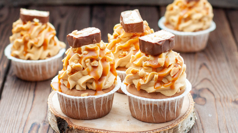 Cupcakes with peanut butter frosting, peanuts, and candy bars