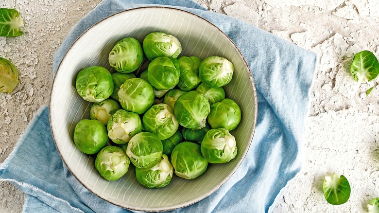 Raw brussels sprouts in a bowl set atop a tea towel