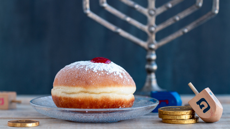 sufganiyah with a menorah, gelt, and two dreidels