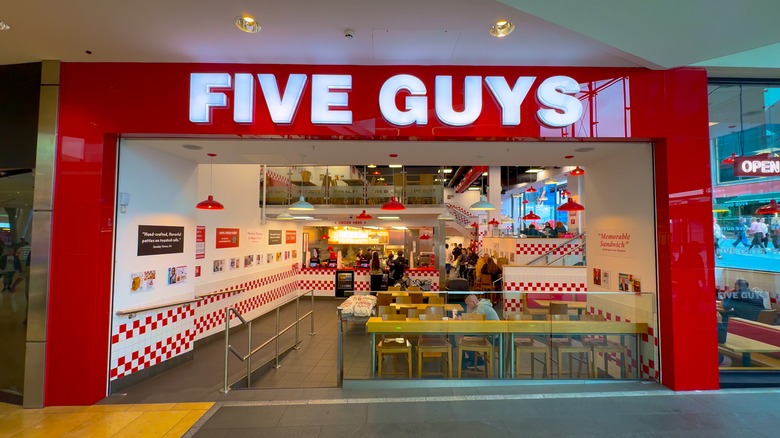 A Five Guys restaurant interior seen from outside.