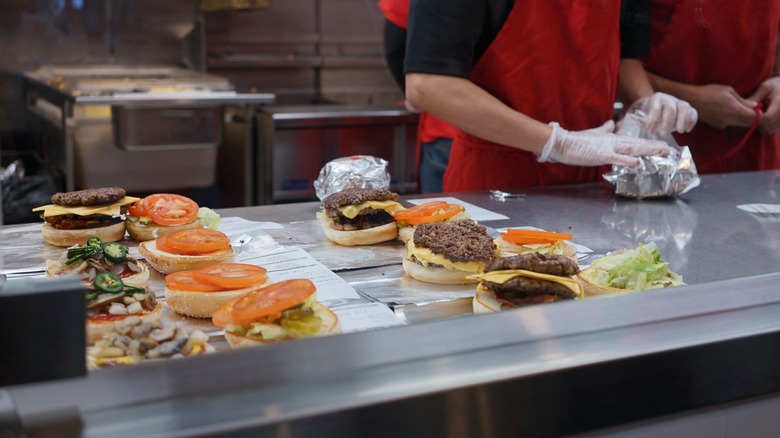 Workers assembling cheeseburgers in a Five Guys kitchen