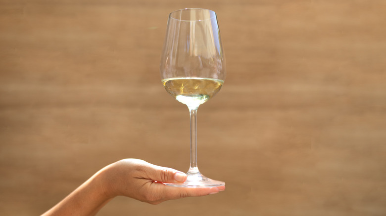 White wine glass in woman's palm