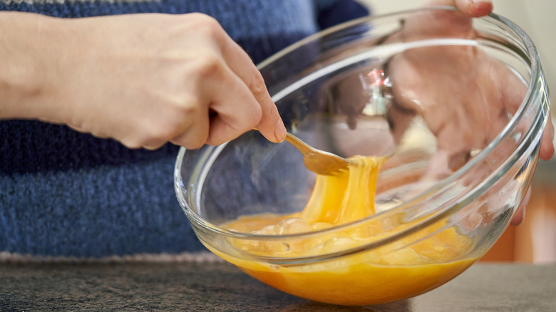 Egg and milk mixture in a white container with a whisk.