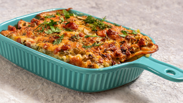 Pizza casserole in a teal container on a light grey surface.