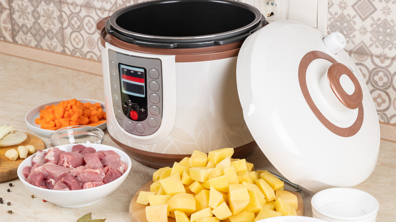 An Instant Pot surrounding by bowls of ingredients ready to go in the slow cooker